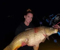 Liz Jenkins holding a large carp catch at night